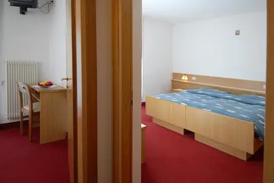 a bedroom with a bed and a desk and a table at Hotel Zanon in Ziano di Fiemme