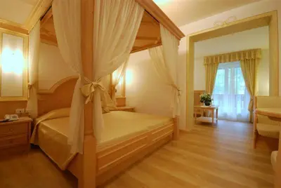 a bedroom with a canopy bed with a large window at Hotel Bellaria in Predazzo