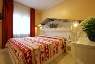 a bedroom with a bed with a red and white blanket at Hotel Bellaria in Predazzo
