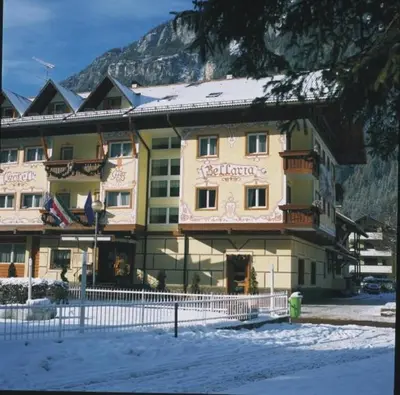 a large building in the snow in front of a mountain at Hotel Bellaria in Predazzo