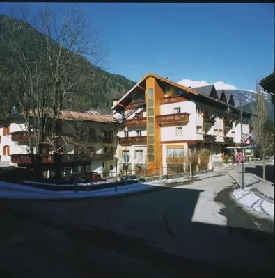 a large building on a street with a stop sign at Hotel Bellaria in Predazzo