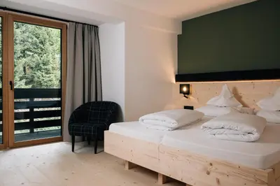 a bedroom with a bed and a chair and a window at Hotel Jägerhof in San Leonardo in Passiria