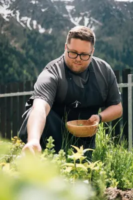 a man in glasses holding a bowl in a garden at Hotel Jägerhof in San Leonardo in Passiria