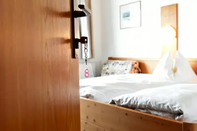 a bedroom with a bed with white sheets at Schönblick OHG des Daum Tobias in Aldino