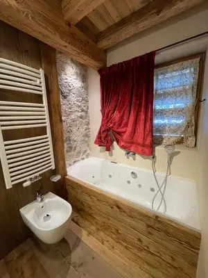 a bathroom with a tub and a toilet and a red curtain at Luxury Cortina in Cortina dʼAmpezzo