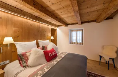 a bedroom with a bed in a room with wooden ceilings at Luxury Cortina in Cortina dʼAmpezzo