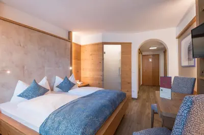 a bedroom with a large bed and a desk at Posthotel Lamm in Vipiteno