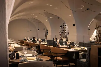 a restaurant with tables and chairs and chandeliers at Posthotel Lamm in Vipiteno