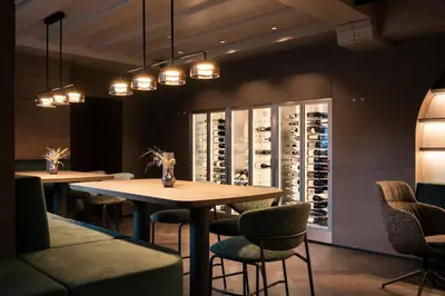a tasting room with two tables and chairs and a wine cellar at Posthotel Lamm in Vipiteno