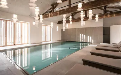 an indoor swimming pool with blue water in a building at Posthotel Lamm in Vipiteno