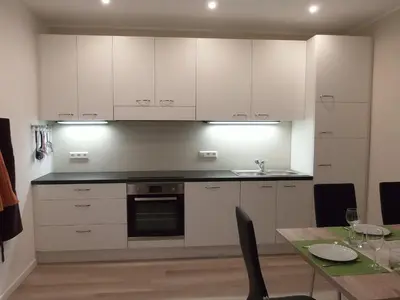 a kitchen with white cabinets and a dining table at Villa Wally in Merano