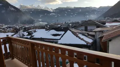 a view of a town with snow covered roofs on a balcony at Casa Bedovina in Predazzo