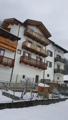 a building with wooden balconies in the snow at Casa Bedovina in Predazzo