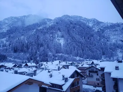 a village covered in snow with a mountain in the background at Casa Bedovina in Predazzo