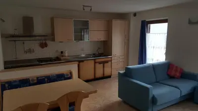 a living room with a blue couch and a kitchen at Casa Bedovina in Predazzo