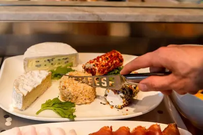 a person eating a plate of food with a fork and knife at Hotel Garni Günther in Postal