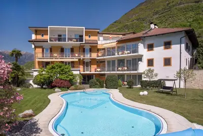 a villa with a swimming pool in front of a building at Hotel Garni Günther in Postal