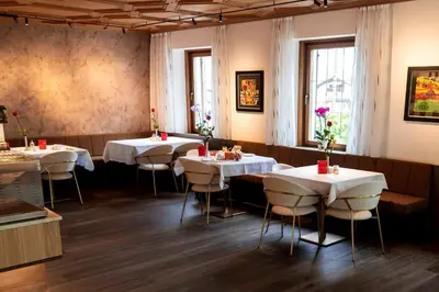 a restaurant with white tables and chairs in a room at Hotel Garni Günther in Postal