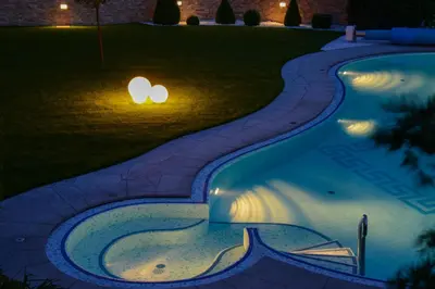 a swimming pool at night with lights in the grass at Hotel Garni Günther in Postal