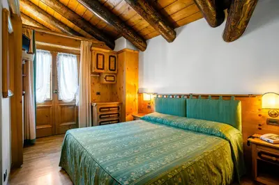 a bedroom with a bed in a room with wooden ceilings at Hotel Natale in Cortina dʼAmpezzo