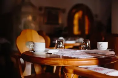 a wooden table with cups and saucers on it at Hotel Natale in Cortina dʼAmpezzo