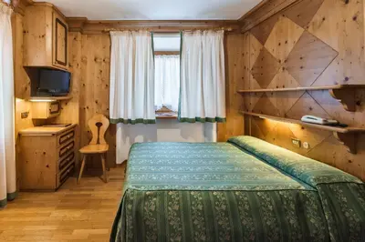 a bedroom with a bed and a television at Hotel Natale in Cortina dʼAmpezzo