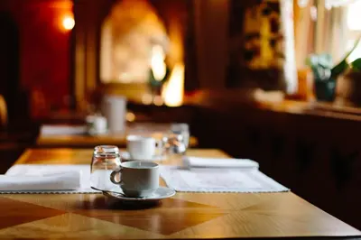a wooden table with a cup of coffee on it at Hotel Natale in Cortina dʼAmpezzo
