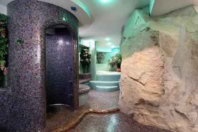 a bathroom with a large rock wall next to a bath tub at Hotel Natale in Cortina dʼAmpezzo
