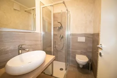a bathroom with a shower and a sink and a toilet at Casa Ciroch in Moena
