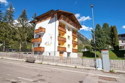 a building with balconies and a fence next to a street at Casa Ciroch in Moena