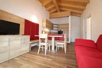 a living room with a red couch and a table with chairs at Casa Ciroch in Moena