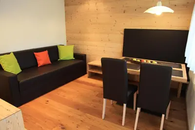 a living room with a black couch and a table at Appartements Mutschlechner in Valdaora