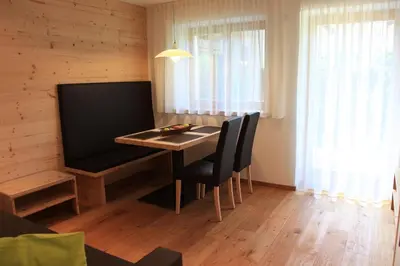 a dining room with a table with chairs and a television at Appartements Mutschlechner in Valdaora