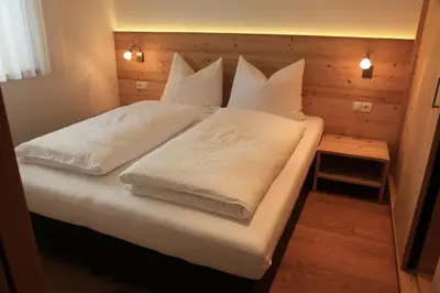 a bedroom with two beds with white sheets and pillows at Appartements Mutschlechner in Valdaora