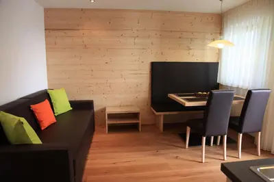 a living room with a black couch and a table at Appartements Mutschlechner in Valdaora