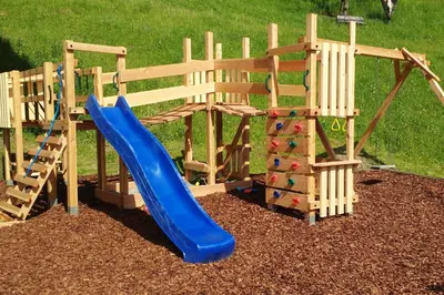 a playground with a blue slide and a rock wall at Thalhofer Hof in Lazfons