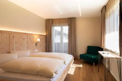 a hotel room with two beds and a green chair at Bed&Breakfast Pension Hilpold in Lana