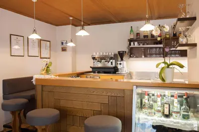 a bar with two stools and a counter with bottles at Bed&Breakfast Pension Hilpold in Lana