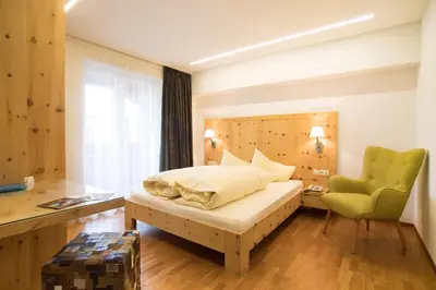 a bedroom with a bed and a green chair at Bed&Breakfast Pension Hilpold in Lana