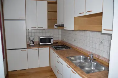 a kitchen with white cabinets and a sink and a microwave at Haus Hofer in Barbiano