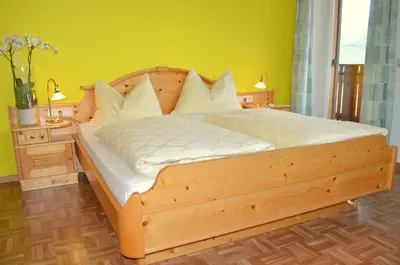 a wooden bed in a bedroom with a yellow wall at Haus Hofer in Barbiano