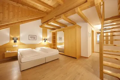 a bedroom with a bed in a room with wooden ceilings at Hotel Goldene Rose in Brunico