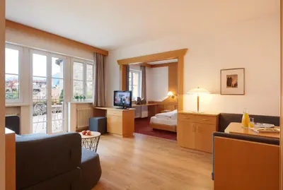 a hotel room with a living room with a bed and a television at Hotel Goldene Rose in Brunico