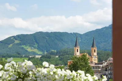 a town with two church towers and a mountain at Hotel Goldene Rose in Brunico