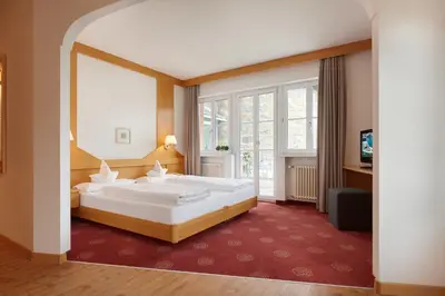 a bedroom with a large bed and a large window at Hotel Goldene Rose in Brunico