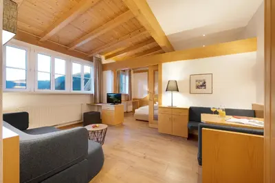 a living room with a couch and a bed at Hotel Goldene Rose in Brunico