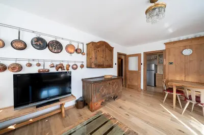 a living room with a flat screen tv and a table at Casa del Salice in Carano