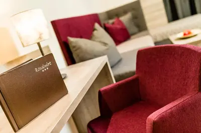 a room with two red chairs and a table with a lamp at Rösslwirt in Barbiano
