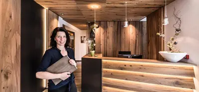 a woman standing in front of a wooden counter at Rösslwirt in Barbiano