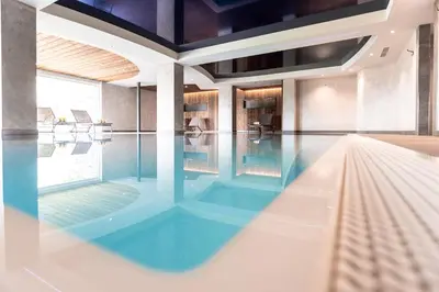 a swimming pool with blue water in a building at Hotel Zum Löwen - Al Leone in Meltina